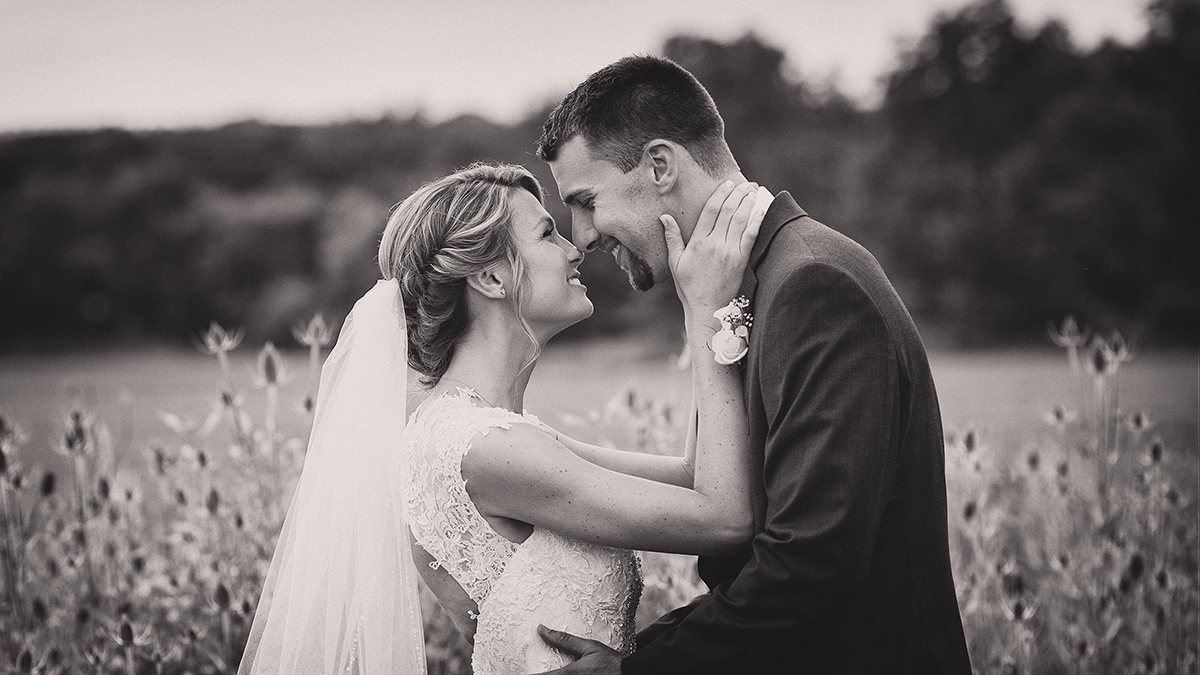 Black-and-white portrait of a bride and groom with foreheads gently together