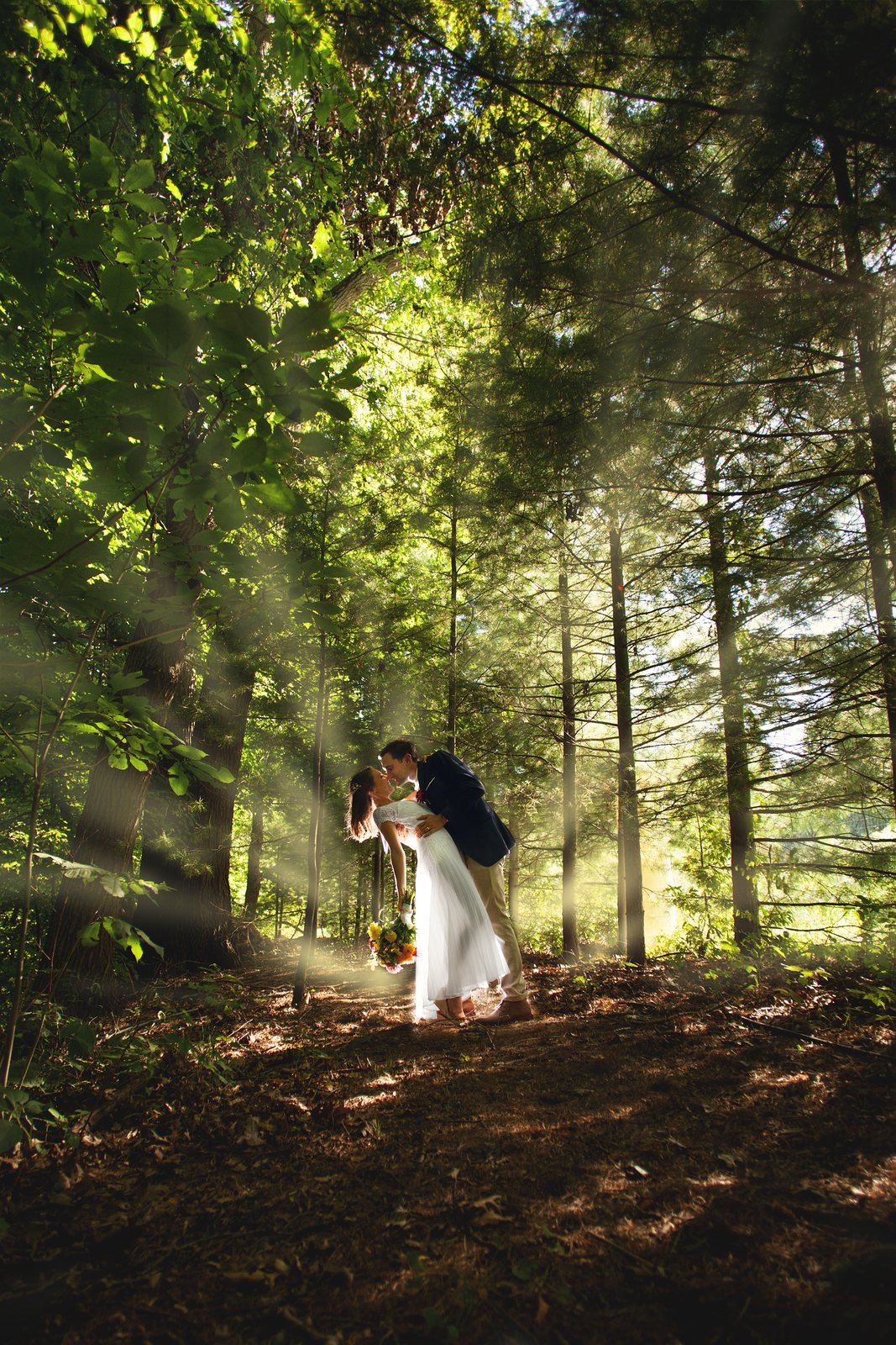Bride and groom embracing in a sun-dappled Michigan forest