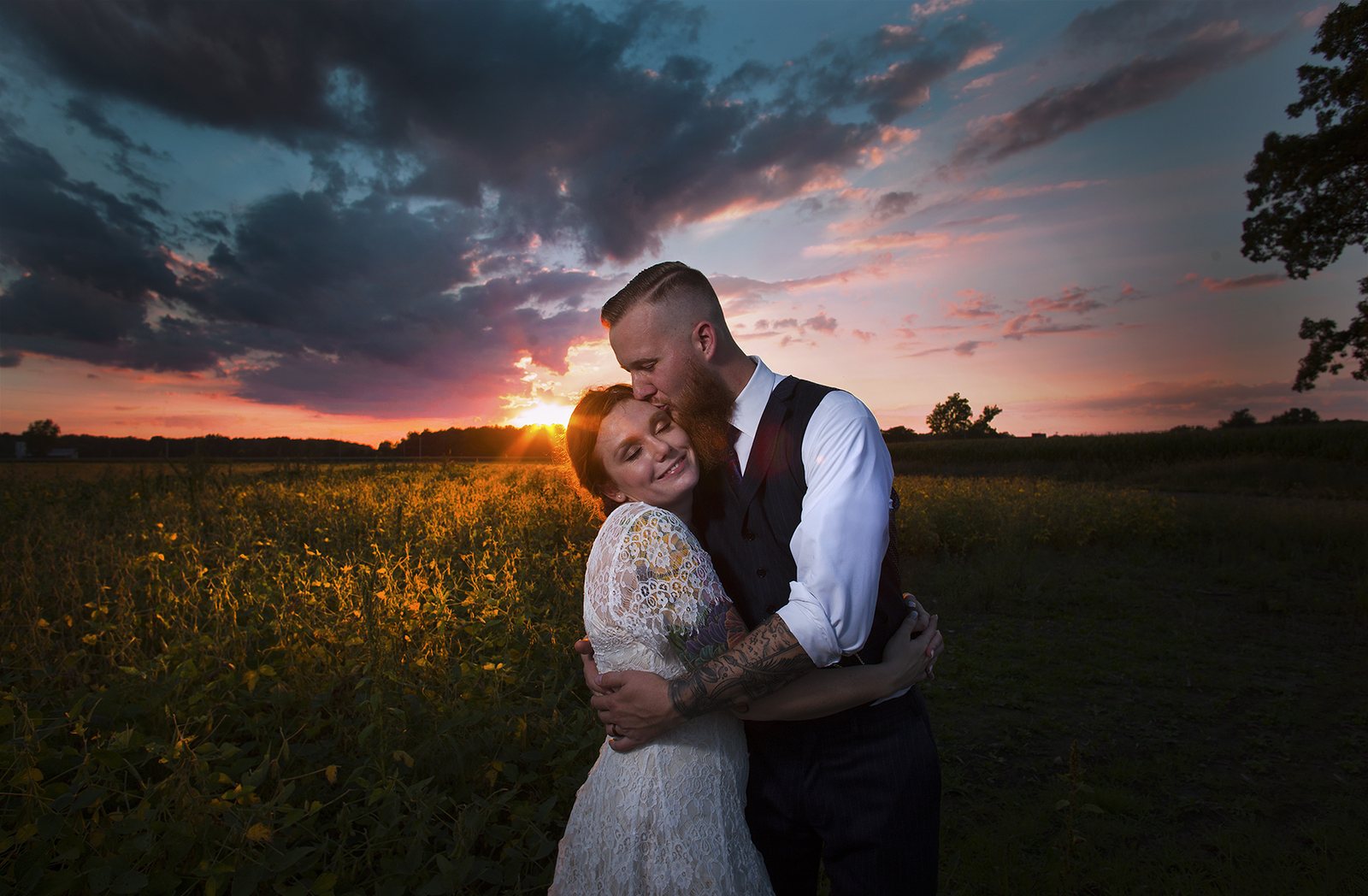 Newlyweds embracing at golden hour in an open field