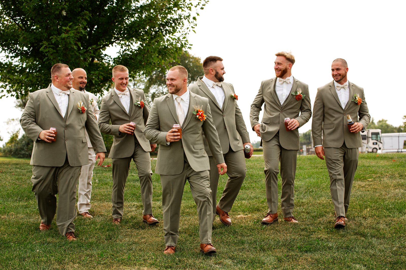 Groom and groomsmen in sage-green suits walking together outdoors